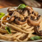 Creamy King Oyster Mushrooms in Pasta with Cashew Cream garnished with fresh basil, served on a white plate for a vegan-friendly meal