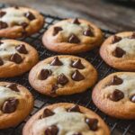 Freshly baked Ghirardelli chocolate chip cookies cooling on a rack, showcasing their golden-brown edges and soft centers